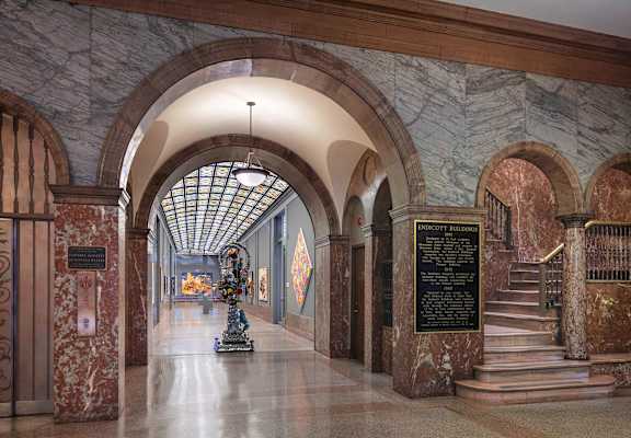 A long hallway with a statue in the middle and a plaque on the wall.