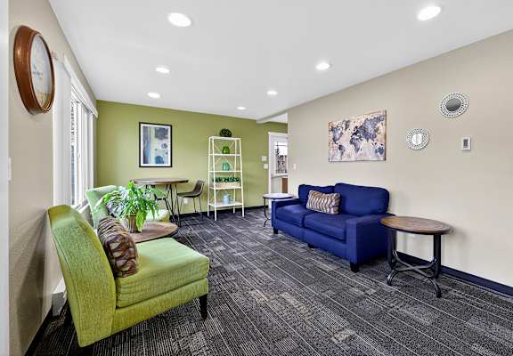 A living room with a green chair and a blue couch.
