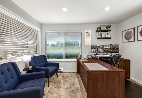 A room with two blue chairs and a wooden desk.