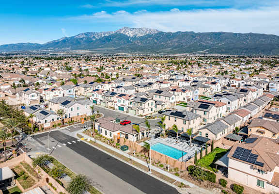 A suburban neighborhood with houses and a street in the foreground.