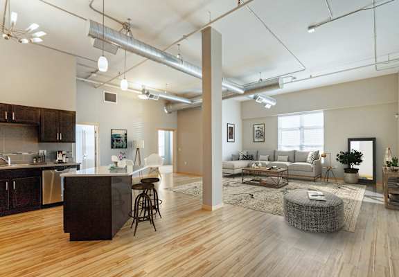 A modern open plan living and kitchen area with wooden floors and a large island.