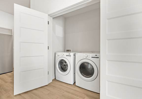 Two white front load washing machines in a laundry room.