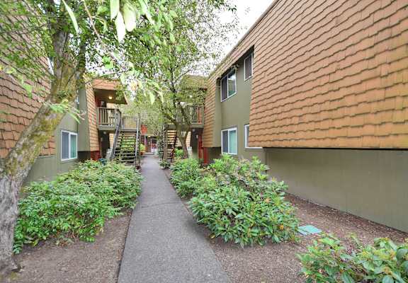 a walkway between two buildings with plants and trees