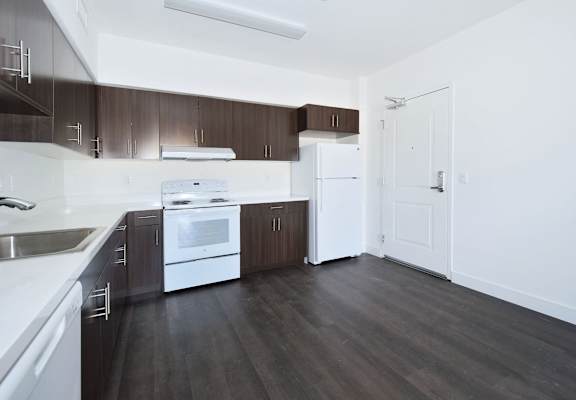 an empty kitchen with white appliances and wooden cabinets