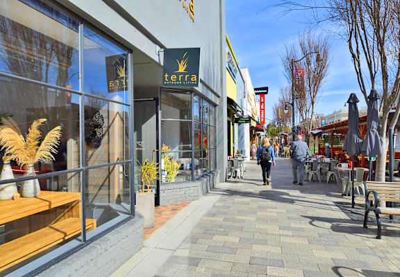 people walking down a sidewalk in front of shops and restaurants