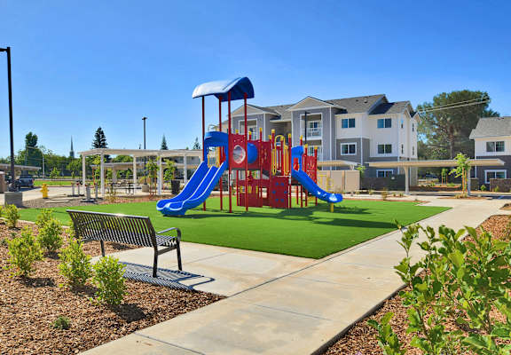 a playground with a swing set and a bench in front of an apartment building