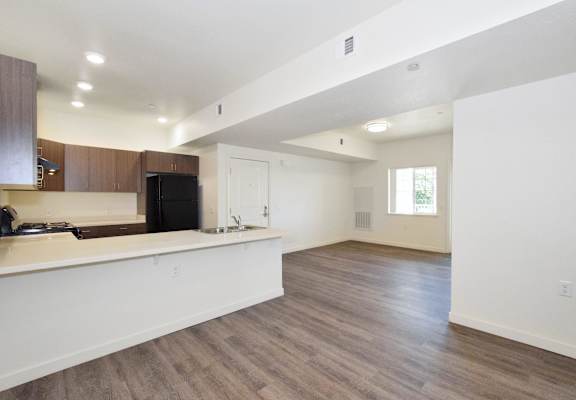 an empty living room and kitchen with white walls and wood flooring