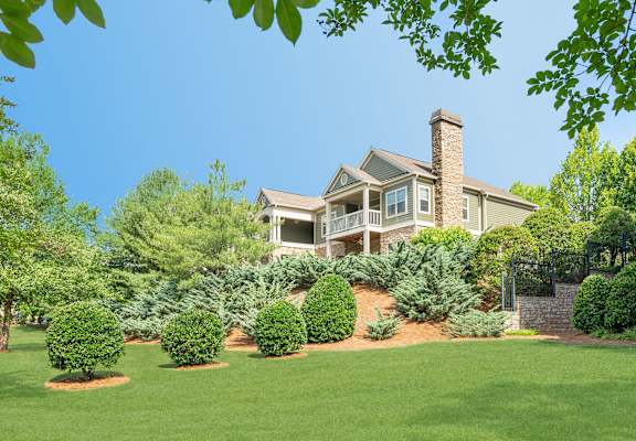 A large house with a green lawn and trees in the front yard.