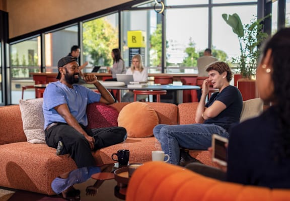 a group of people sitting on a couch talking in a room