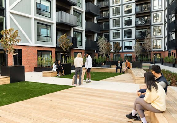 people sitting on a wooden deck in front of an apartment building