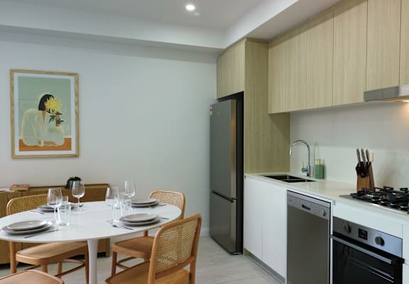 A modern kitchen with a dining table set for two.