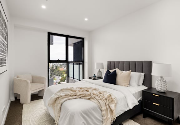 A bedroom with a large bed and a chair.