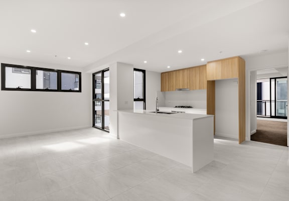 A modern kitchen with a white countertop and wooden accents.