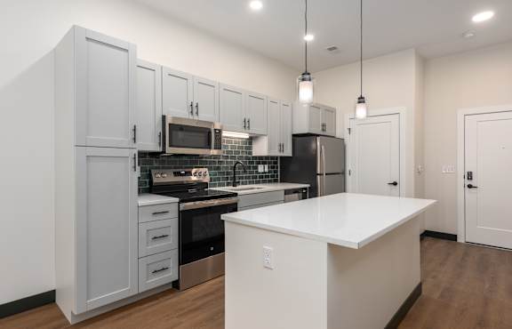 A kitchen with a white countertop and grey cabinets.
