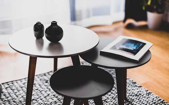 Two black vases are placed on a black table with a book on it.