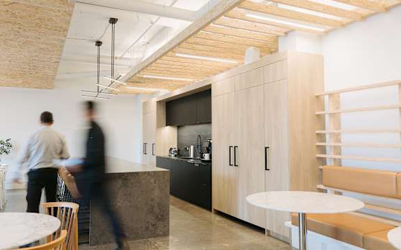 A man in a white shirt is walking through a modern kitchen.