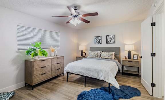 A bedroom with a bed, dresser, and ceiling fan.