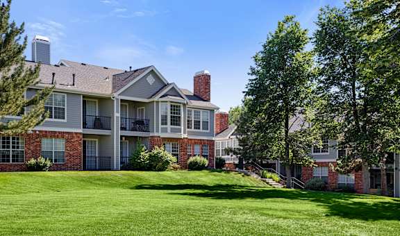 A large, well-maintained apartment complex with a green lawn in front.
