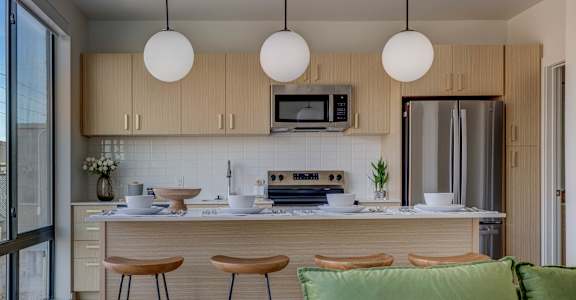 A kitchen with a refrigerator, stove, and bar stools.