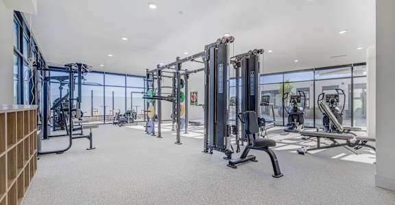 A gym with a variety of equipment including treadmills, weights, and exercise machines.