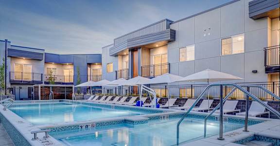 A large outdoor swimming pool with lounge chairs and umbrellas.