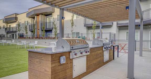 A wooden outdoor kitchen with a grill and sink.