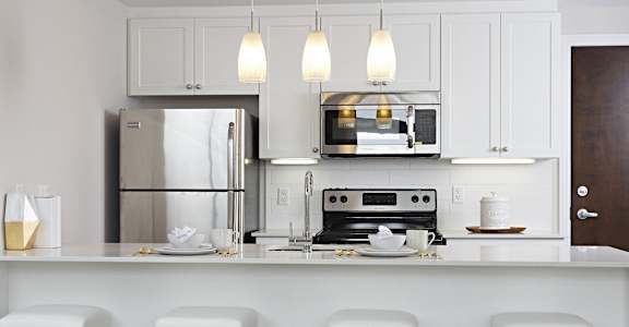 a kitchen with white cabinets and a bar with white stools