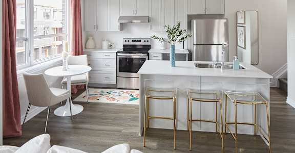 a kitchen with white cabinets and a white island with gold chairs