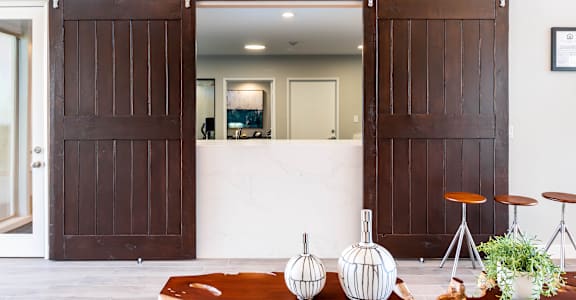 A white interior with a brown door and a white table with a plant on it.