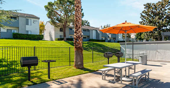 A bright orange umbrella is on a table outside a building.