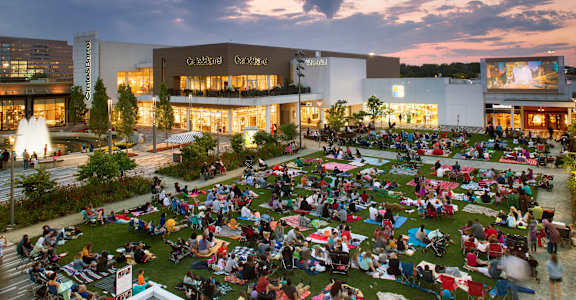A large group of people are sitting on the grass in front of a building.