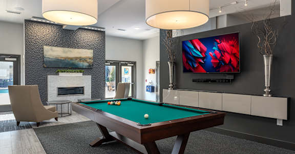 A room with a pool table and a television mounted on the wall.