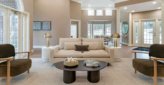 A living room with a white couch and a coffee table in the middle.