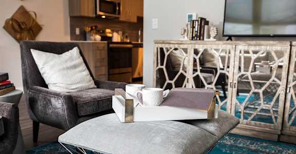 A grey couch with a white pillow sits in a room with a blue rug at The Nines Apartment Homes Apartments, Allentown, PA, 18101