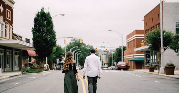 a man and woman walking down the middle of a street
