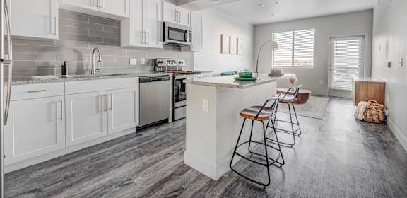 a kitchen with white cabinets and a bar with stools