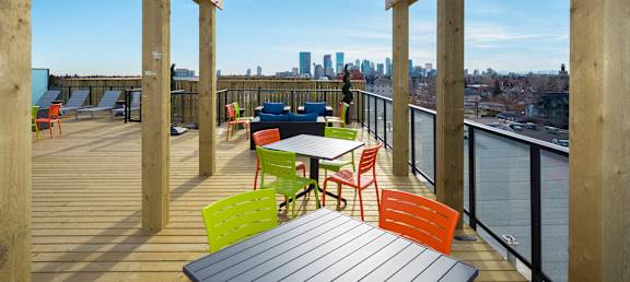 A wooden deck with a table and chairs overlooking a city skyline.