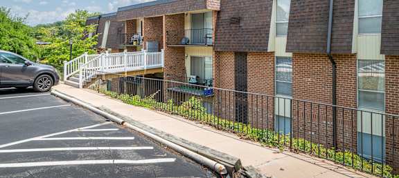 a brick apartment building with a balcony and a parking lot