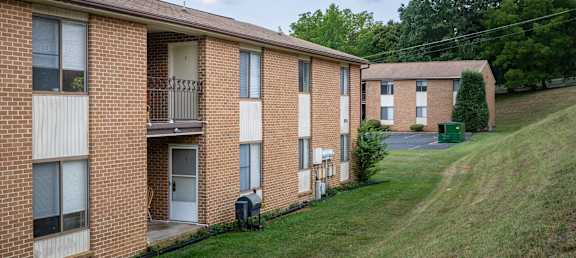 a row of brick apartment buildings on a hill with a grass field