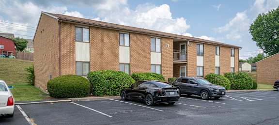an apartment building with two cars parked in a parking lot