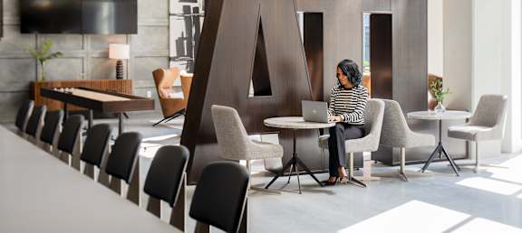 A woman is sitting at a table in a modern office space.