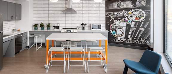 a kitchen with a white table and orange stools