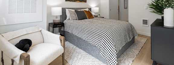 A bedroom with a bed, a chair, and a painting on the wall.