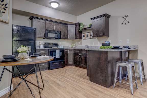 A kitchen with a black refrigerator, black cabinets, and a black island.