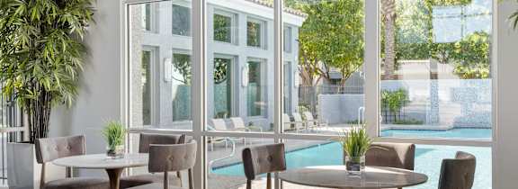 A table with chairs is in front of a glass wall.
