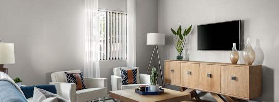 A living room with a blue sofa, a wooden coffee table, and a TV on a cabinet.