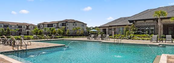 A large swimming pool with a fountain in the middle and chairs around it.