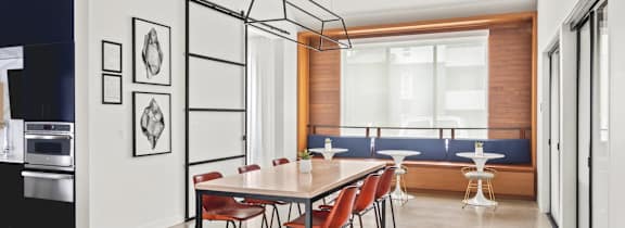 A modern dining room with a long table and chairs.