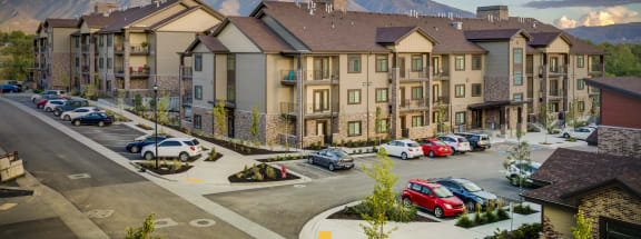 a large apartment complex with a parking lot and mountains in the background