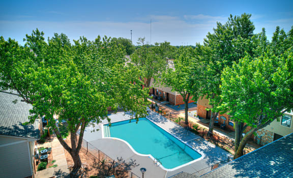 an aerial view of a swimming pool with trees and a resort style pool